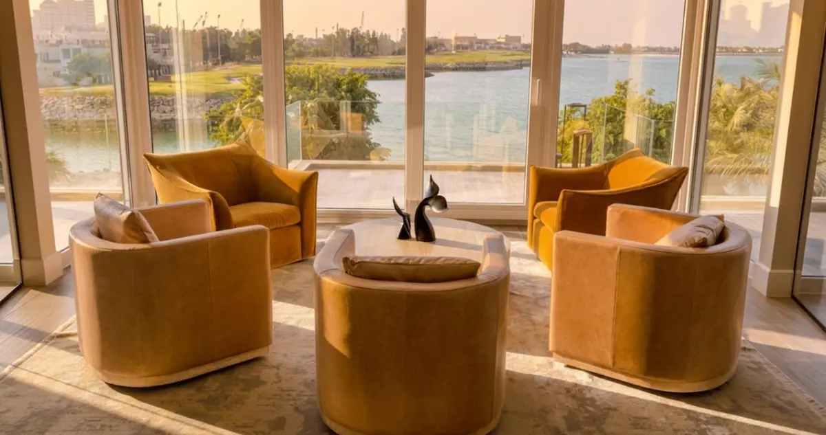 A contemporary office meeting area in Ras Al Khaimah featuring sleek leather chairs, a custom marble conference table, and warm natural lighting from floor-to-ceiling windows overlooking the city skyline. Designed for professional human collaboration.