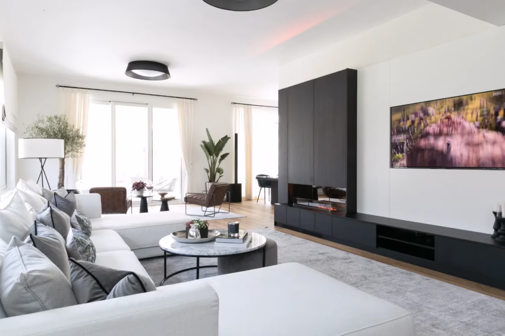 A close-up view of a custom living room media installation. A television is seamlessly recessed into sleek cabinetry with integrated ambient LED lighting. The image highlights the clean, uncluttered design achieved by hiding technology, as described in the text.