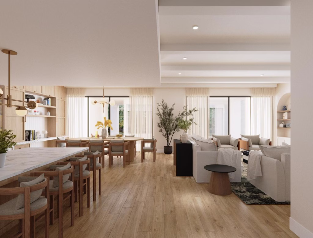 Interior architecture view from the kitchen island looking across the dining and living spaces toward large glass doors leading out to the garden.
