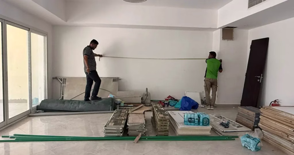 Two contractors measuring a white wall inside an active villa renovation site for the Villa Barefoot project by Tünde Hendricks Design.