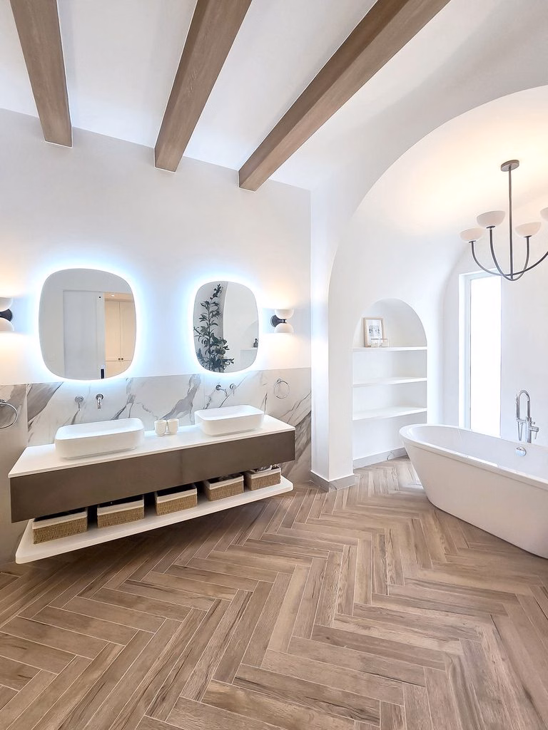 Custom floating double vanity with vessel sinks, wall-mounted fixtures, woven storage baskets, and backlit LED vanity mirrors.